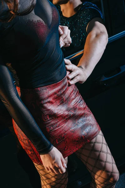 Vue recadrée du client touchant prostituée séduisante en jupe rouge debout près de la voiture — Photo de stock
