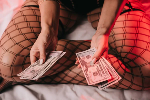 Close up de mulher sentada na cama enquanto segurando dinheiro — Fotografia de Stock