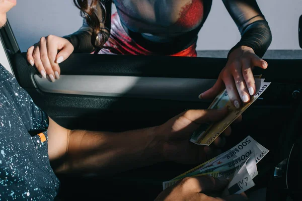 Cropped view of man in car giving money to prostitute — Stock Photo