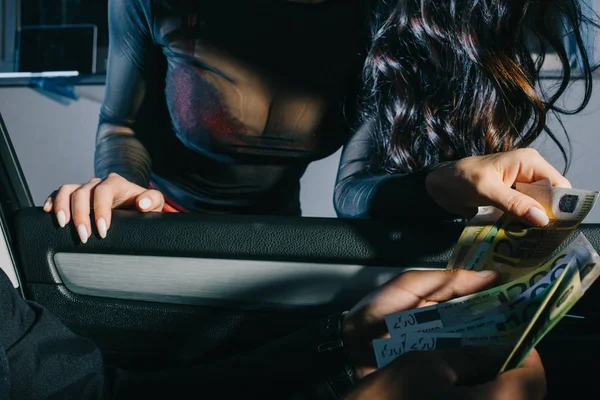 Cropped view of client in car holding euro banknotes near prostitute — Stock Photo