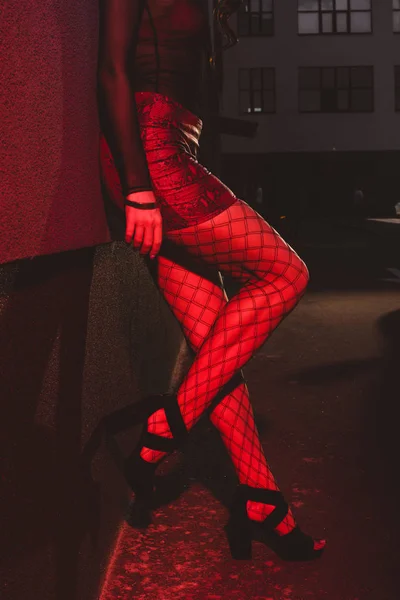 Обрізаний вид жінки в червоній спідниці, що стоїть біля стіни — стокове фото