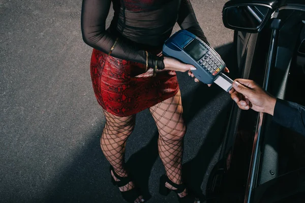 Vista aérea del cliente pagando con tarjeta de crédito mientras prostituta sostiene lector de tarjetas de crédito - foto de stock