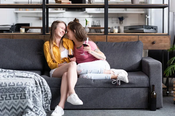 Дві лесбіянки тримають келихи для вина, сидячи на дивані у вітальні — стокове фото