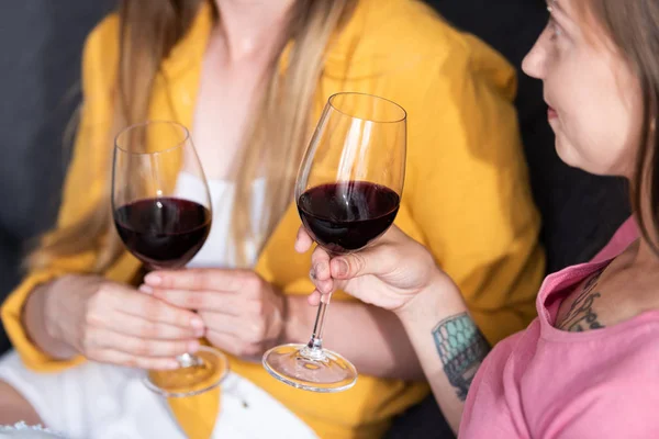 Частичный вид двух лесбиянок, держащих бокалы с вином в гостиной — стоковое фото