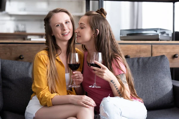 Deux lesbiennes tenant des verres à vin tout en étant assis sur le canapé dans le salon — Photo de stock