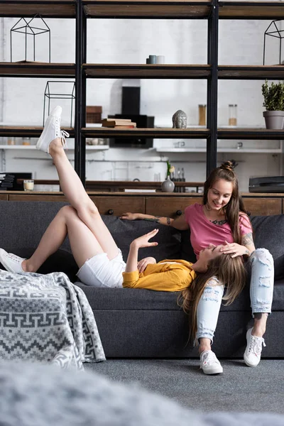 Due lesbiche sorridenti sul divano in accogliente soggiorno — Foto stock
