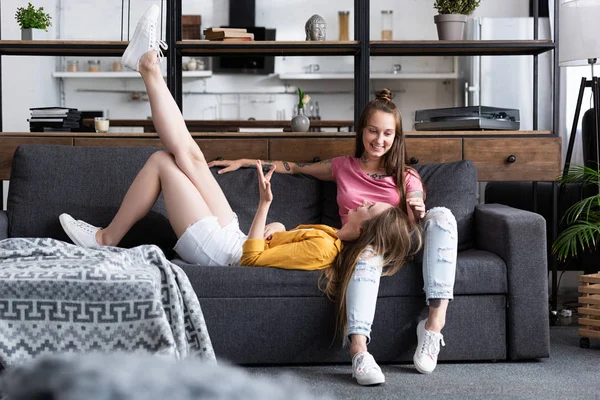 Deux lesbiennes souriantes sur le canapé dans le salon confortable — Photo de stock