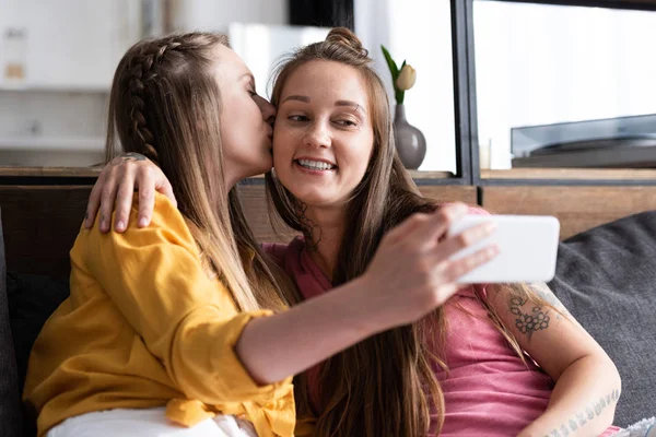 Lesbica in camicetta gialla baciare fidanzata mentre prende selfie — Foto stock