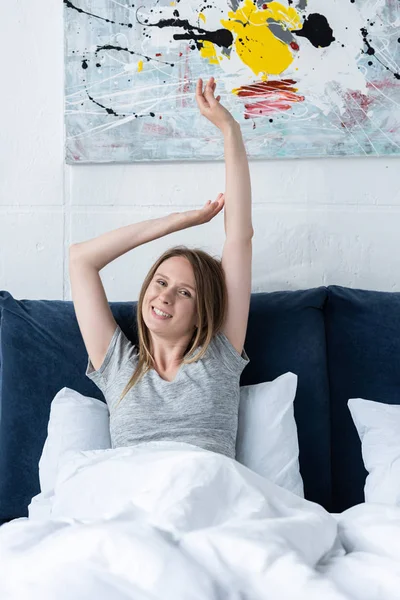 Щаслива молода жінка в ліжку дивиться на камеру вранці — стокове фото