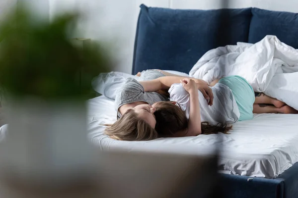 Enfoque selectivo de dos lesbianas abrazando mientras yacen en la cama - foto de stock