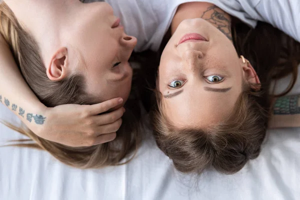 Vista superior de dos lesbianas abrazándose mientras yacen en la cama - foto de stock