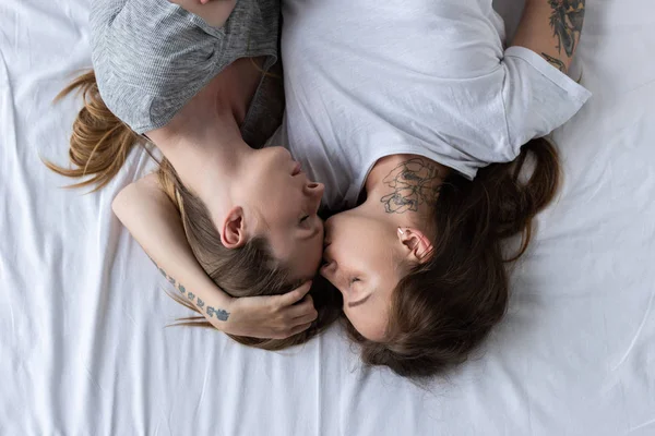 Vista superior de dos lesbianas abrazándose y besándose en la cama - foto de stock