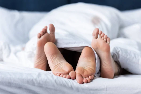 Partial view of two barefoot lesbians lying under blanket — Stock Photo