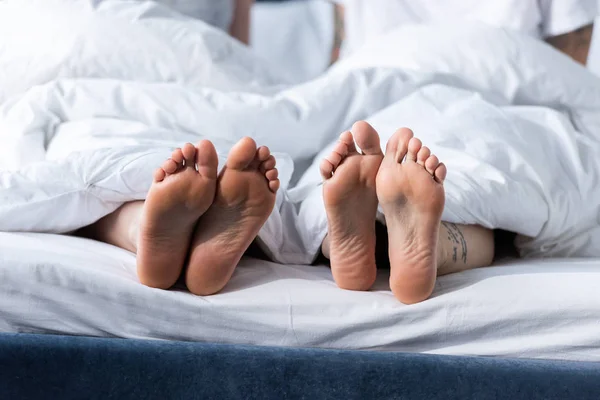 Vista parcial de dois descalços lésbicas deitado sob cobertor — Fotografia de Stock