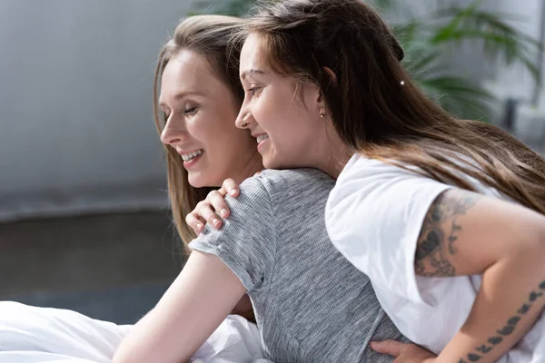 Две счастливые лесбиянки обнимаются на кровати утром — стоковое фото