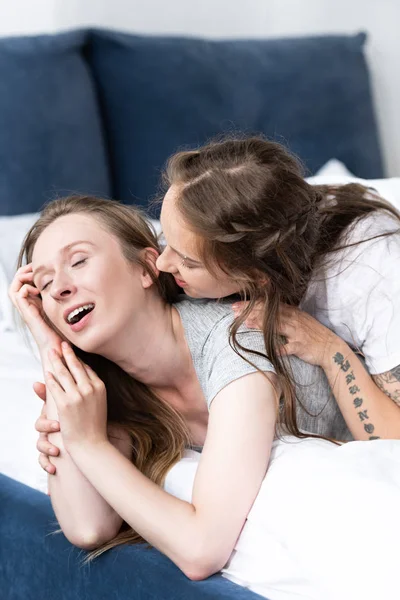 Две счастливые лесбиянки обнимаются на кровати утром — стоковое фото