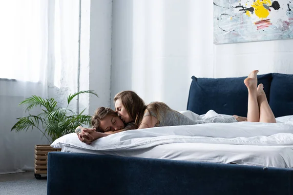 Две лесбиянки держатся за руки и целуются, лежа на кровати по утрам — стоковое фото
