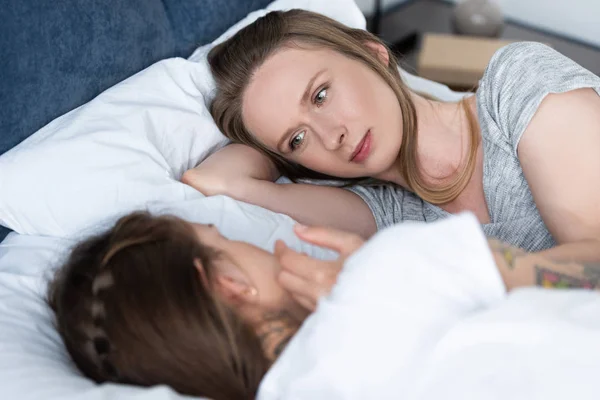 Selective focus of two lesbians looking at each other while lying in bed — Stock Photo