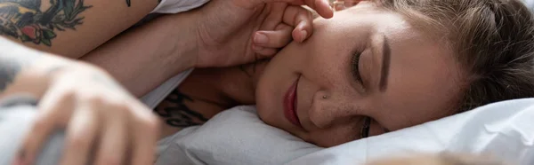 Panoramic shot of two lesbians touching each other while lying in bed — Stock Photo