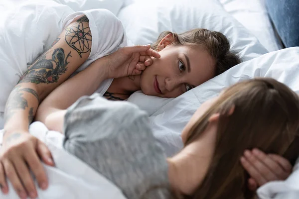 Вибірковий фокус двох лесбійок, які дивляться один на одного, лежачи в ліжку — стокове фото