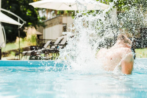 Mann in Schwimmbad in der Nähe von Wasserspritzern im Fokus — Stockfoto
