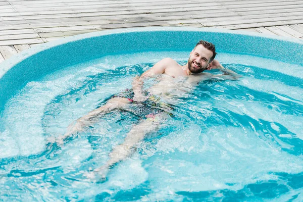 Homem barbudo feliz na piscina olhando para a câmera — Fotografia de Stock