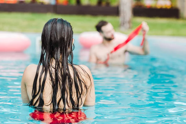 Vue arrière de la femme nageant dans la piscine près de l'homme — Photo de stock