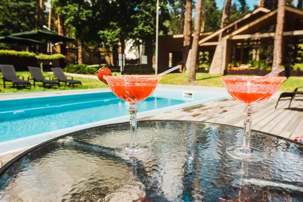 Bicchieri da cocktail con cocktail alcolici sul tavolo vicino alla piscina — Foto stock
