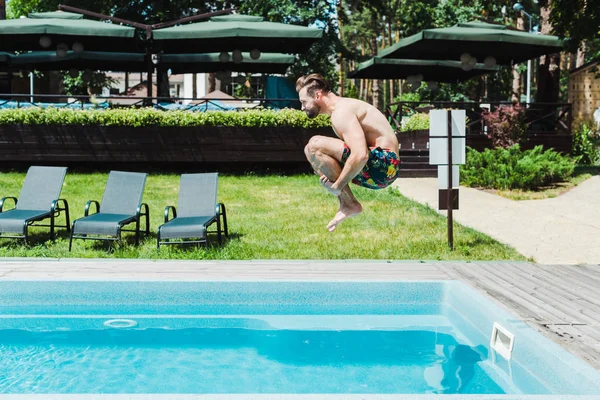 Vista lateral del hombre barbudo con salto descalzo en la piscina — Stock Photo