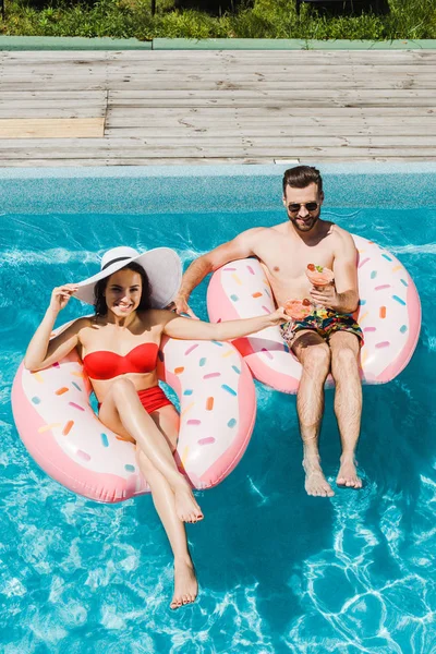 Vue aérienne de la femme en chapeau de paille et bel homme tenant des verres à cocktail — Photo de stock