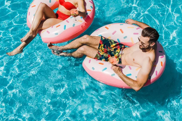 Vue recadrée de la femme près de l'homme en lunettes de soleil avec cocktail — Photo de stock