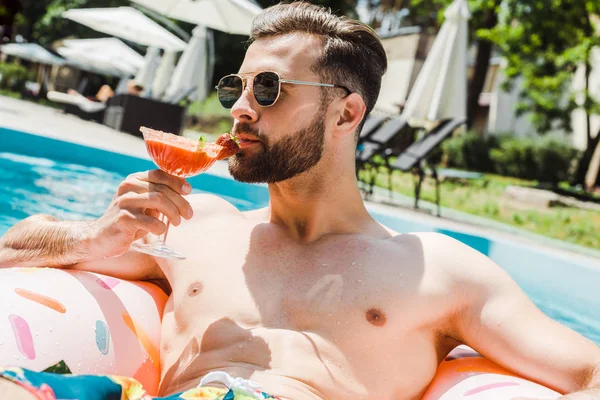 Bel homme barbu dans des lunettes de soleil tenant verre à cocktail — Photo de stock