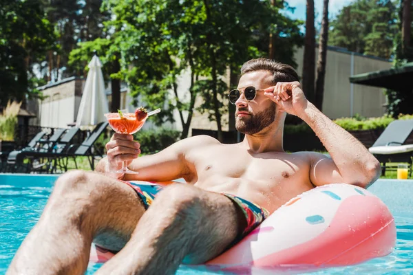 Selektiver Fokus des Mannes, der Sonnenbrille berührt und Cocktailglas in der Hand hält — Stockfoto