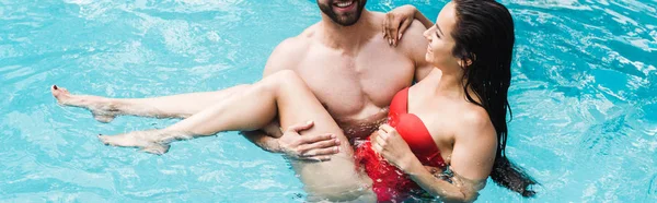 Panoramic shot of bearded man holding in arms brunette woman — Stock Photo