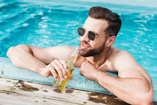 Homem barbudo feliz em óculos de sol segurando garrafa com cerveja — Fotografia de Stock