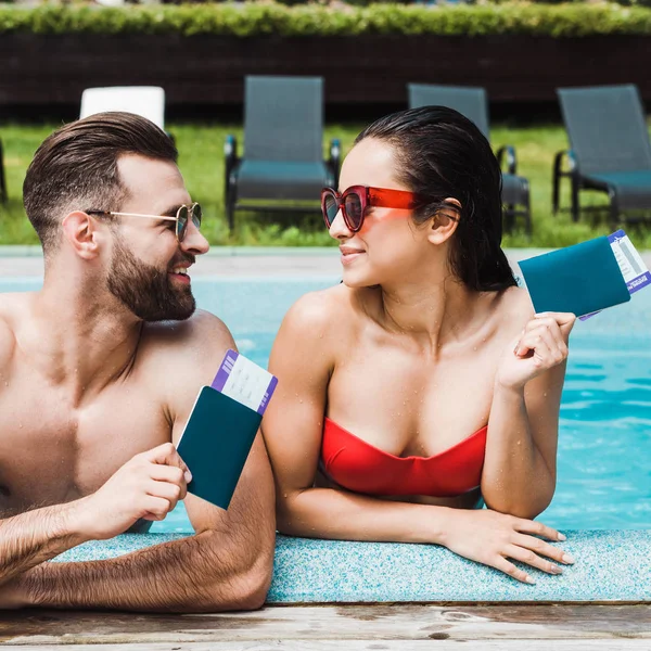 Felice donna e uomo in occhiali da sole in possesso di passaporti con biglietti aerei — Foto stock