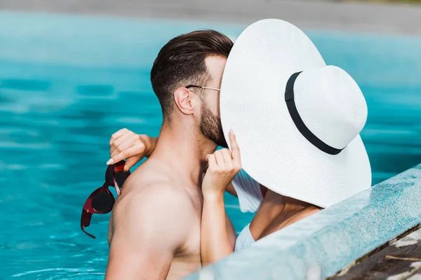 Selective focus of muscular man and young woman in straw hat covering faces — Stock Photo