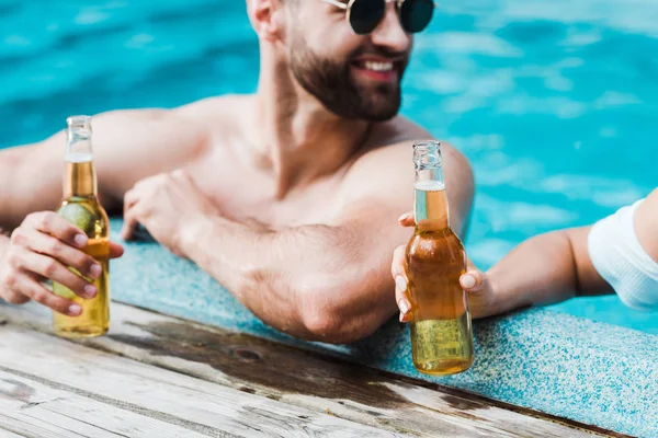 Foco seletivo de homem feliz segurando garrafa com cerveja perto da mulher — Fotografia de Stock