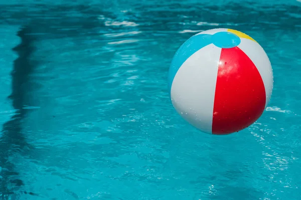 Bola inflable colorida en agua azul en piscina - foto de stock