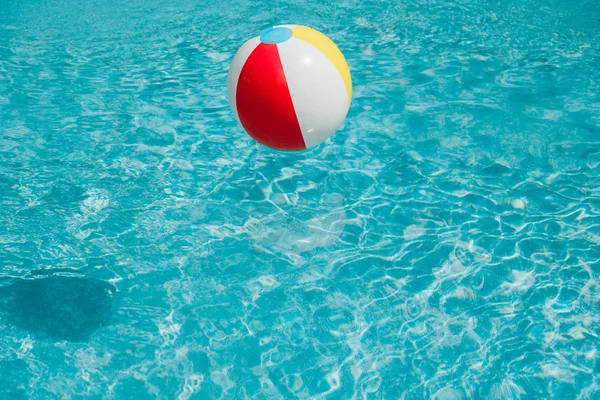 Bola inflable colorida en agua azul limpia en la piscina - foto de stock