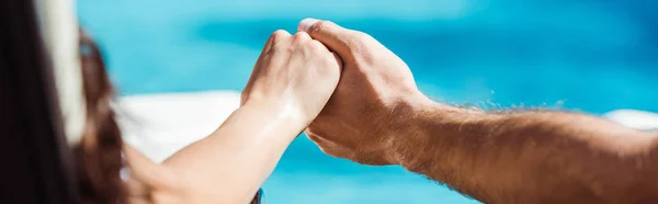 Panoramic shot of man and young woman holding hands near swimming pool — Stock Photo