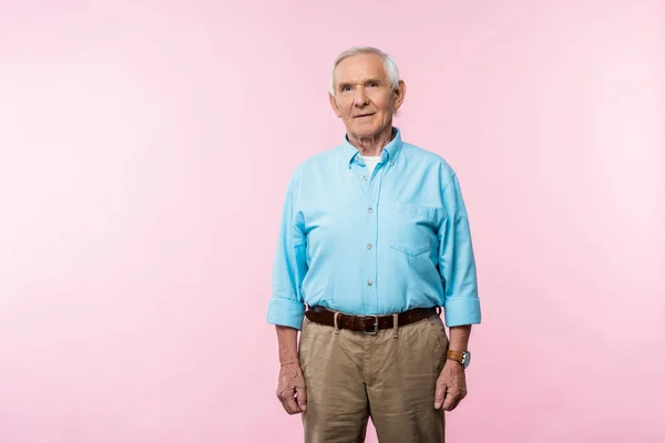 Старший чоловік з сірим волоссям стоїть і дивиться на камеру на рожевому — стокове фото
