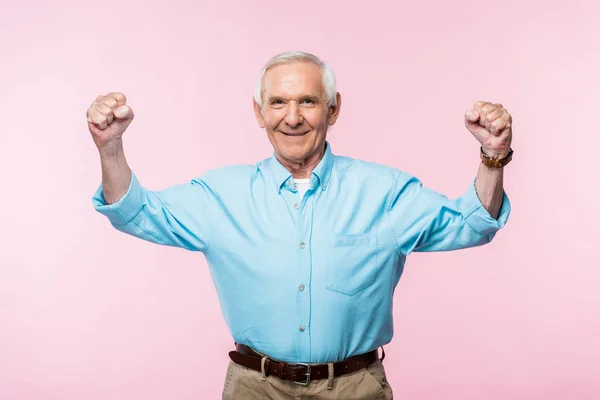 Homem aposentado alegre mostrando punhos e sorrindo em rosa — Fotografia de Stock