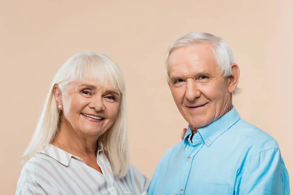 Happy retired couple with grey hair looking at camera isolated on beige — Stock Photo