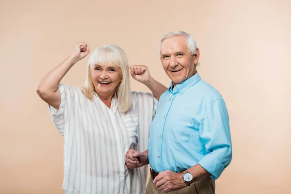 Cheerful senior woman gesturing near happy husband on beige — Stock Photo