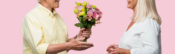 Panoramic shot of senior man giving bouquet of flowers to happy wife isolated on pink — Stock Photo