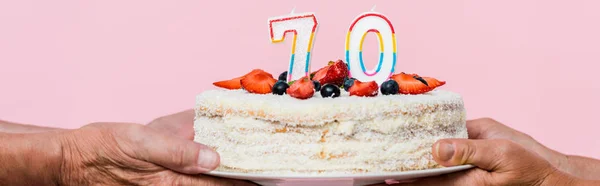 Panoramic shot of retired couple holding birthday cake isolated on pink — Stock Photo