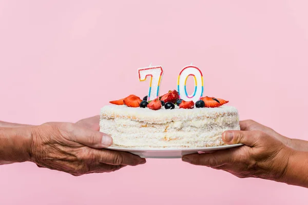 Cropped view of retired couple holding tasty birthday cake isolated on pink — Stock Photo