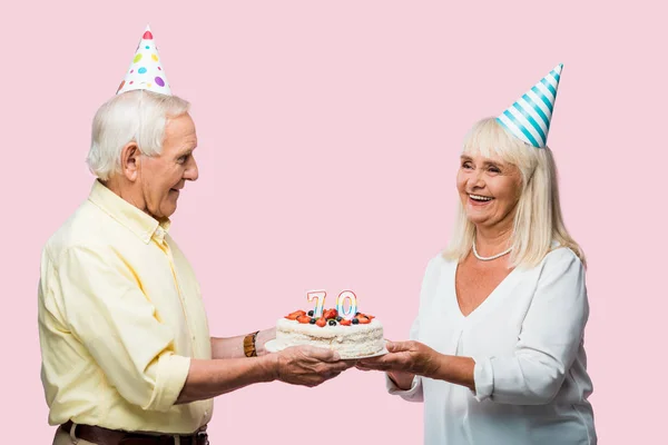 Positive senior couple with grey hair holding birthday cake isolated on pink — Stock Photo