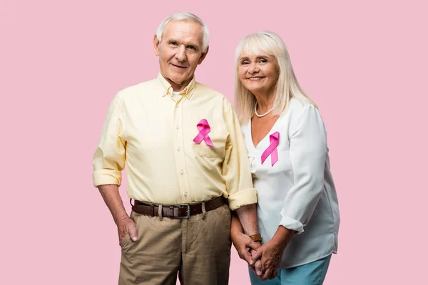 Cheerful retired couple with grey hair and ribbons isolated on pink — Stock Photo